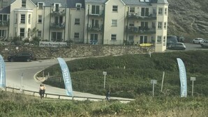 A multi-story building with a flat roof, likely a hotel or residential complex, with a sign reading "Beachcombers" and a view of a hillside. - Beautiful Modern SeaView Apartment in WatergateBay (Newquay)