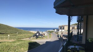 A coastal road with a triangular landmark, a building with a balcony, and a view of the sea. - Beautiful Modern SeaView Apartment in WatergateBay (Newquay)