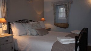 A bedroom with a bed, bedside tables, a hanging light fixture, and a window with curtains. - Petit Vue Vert - One  Bedroom Gite with heated pool on edge of medieval village (Puy-l'Évêque)