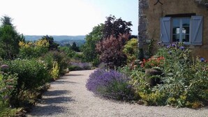 A gravel path leading to a stone building with a garden. - Petit Vue Vert - One  Bedroom Gite with heated pool on edge of medieval village (Puy-l'Évêque)