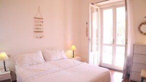 Ein Schlafzimmer mit einem Bett, zwei Nachttischen mit Lampen, einem Kleiderschrank und einer Tür zu einem Außenbereich.