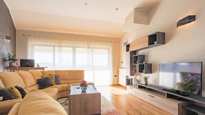 A modern living room with a sofa, coffee table, TV, and built-in shelves.