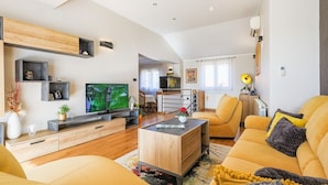 A modern living room with a sofa, coffee table, TV, and built-in shelves.