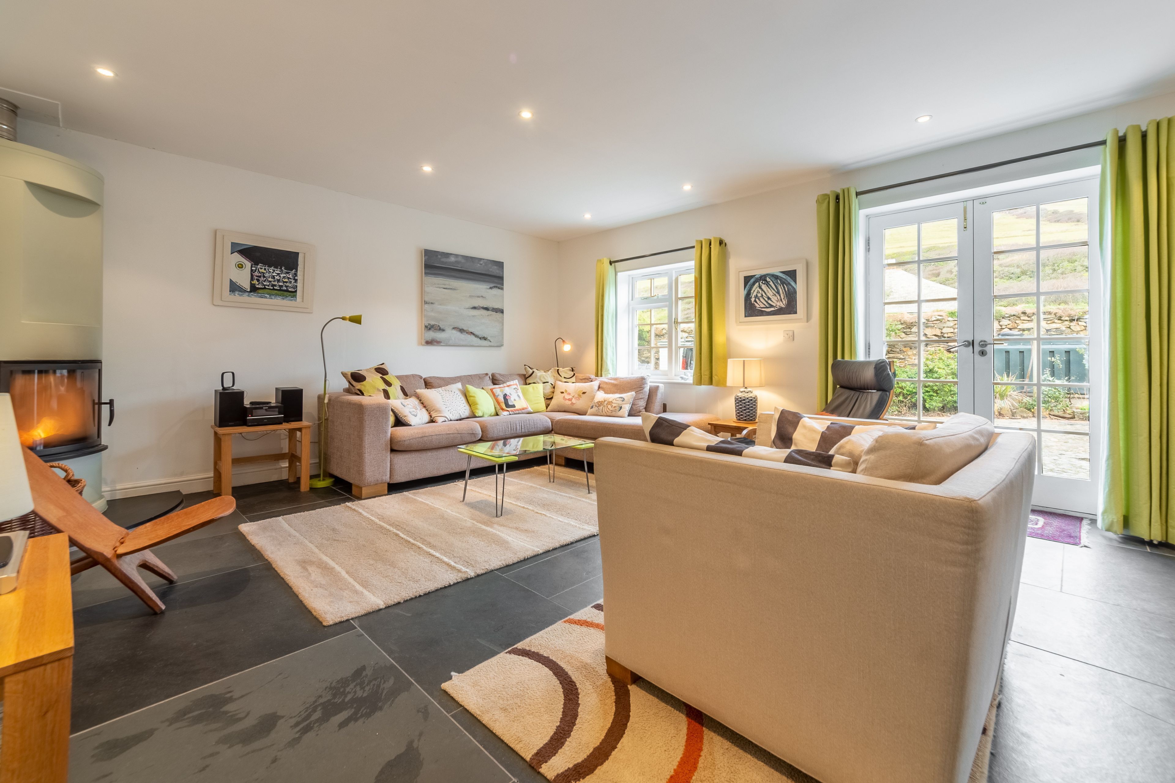 A modern living room with a sofa set, a fireplace, and a large window with curtains.