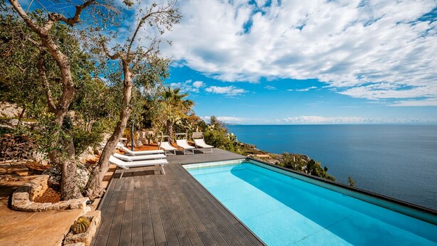 Terraza de madera con piscina, con vista a un cuerpo de agua.
