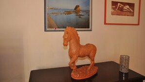A sculpture of a horse on a table, a framed painting of a coastal scene, and a framed photograph. - Typical Salento residence (Alessano)
