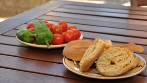 A wooden table with a plate of bread and a plate of tomatoes and peppers. - Typical Salento residence (Alessano)