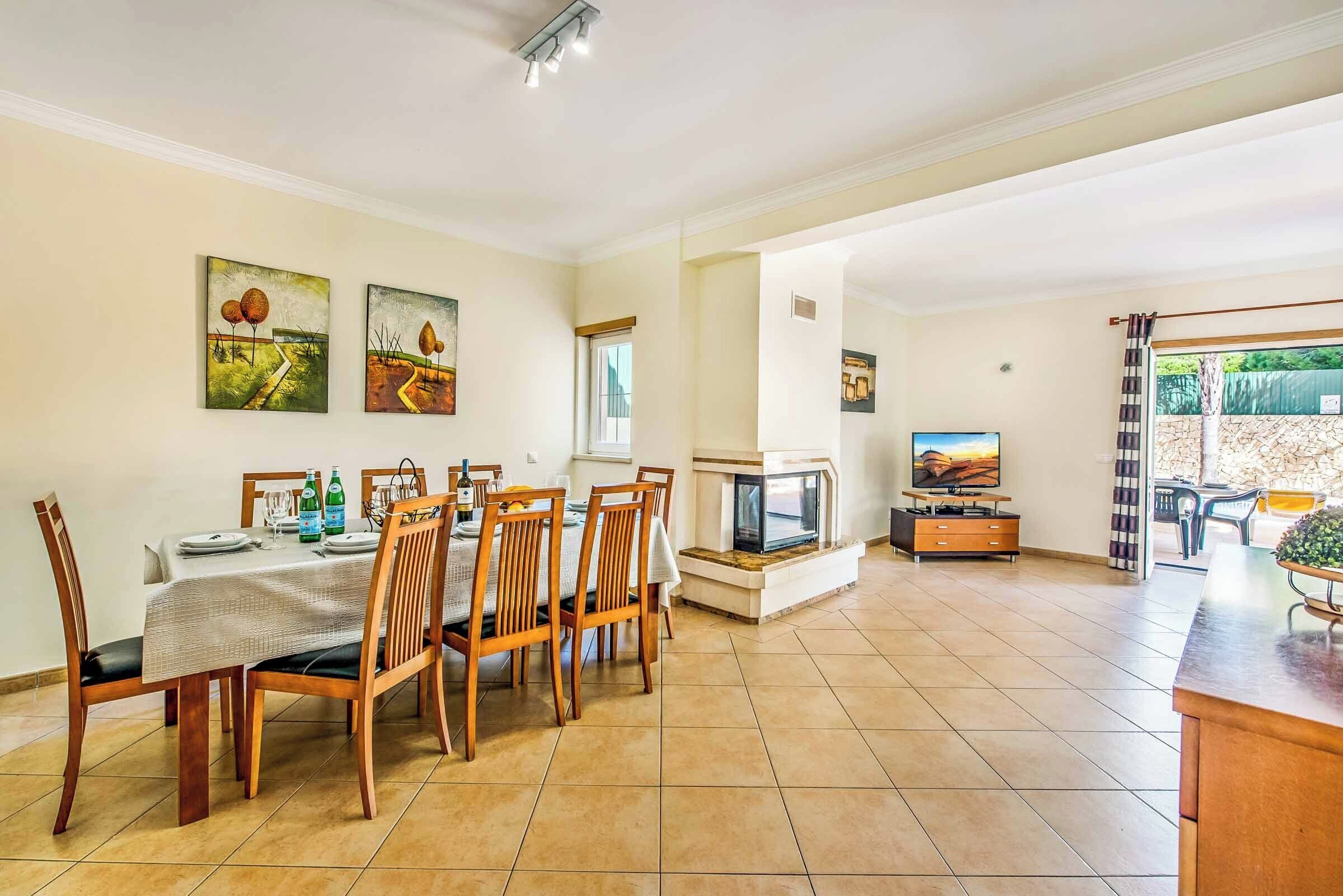 A dining area with a table set for six, wooden chairs, and a fireplace.