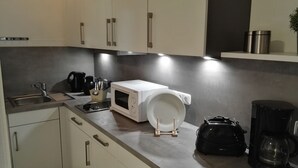 Une cuisine moderne équipée d’un évier, d’une machine à café, d’un four à micro-ondes et d’une bouilloire.