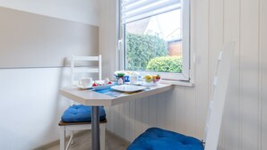 Una habitación pequeña y luminosa con una mesa blanca y un ventanal.