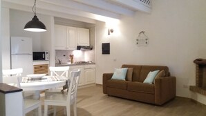 A compact living space with a kitchen, dining area, and a sofa. - 100 meters from the sea Villa immersed in the greenery (Santa Margherita di Pula)