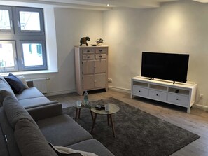 A modern living room with a sofa, a TV, a cabinet, and a window.