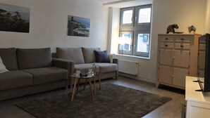 Ein Wohnzimmer mit einer Couch, einem kleinen Tisch, einem Heizkörper und einem Schrank.