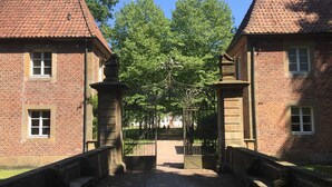 Ein Innenhof mit zwei Backsteingebäuden, einem zentralen Tor und Bänken.