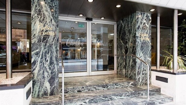 L’entrée d’un hôtel, avec des colonnes de marbre et des portes en verre.