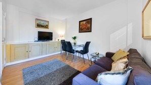 Un salon comprenant un canapé, une table basse, un téléviseur et un coin repas avec des chaises et une table.