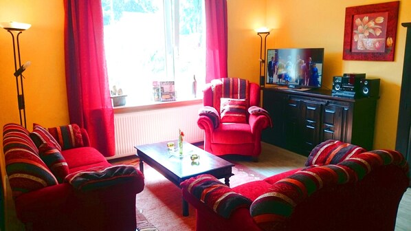Relax in this inviting living room with a sofa, armchairs, and a flat-screen TV.