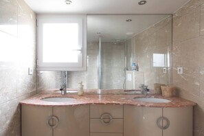 A bathroom with two sinks, a large mirror, and a shower.
