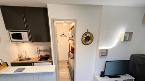 A modern apartment with a kitchen, a living area, and a hallway leading to a bedroom. - Homerez - Studio Allos - Mountain view (Allos)