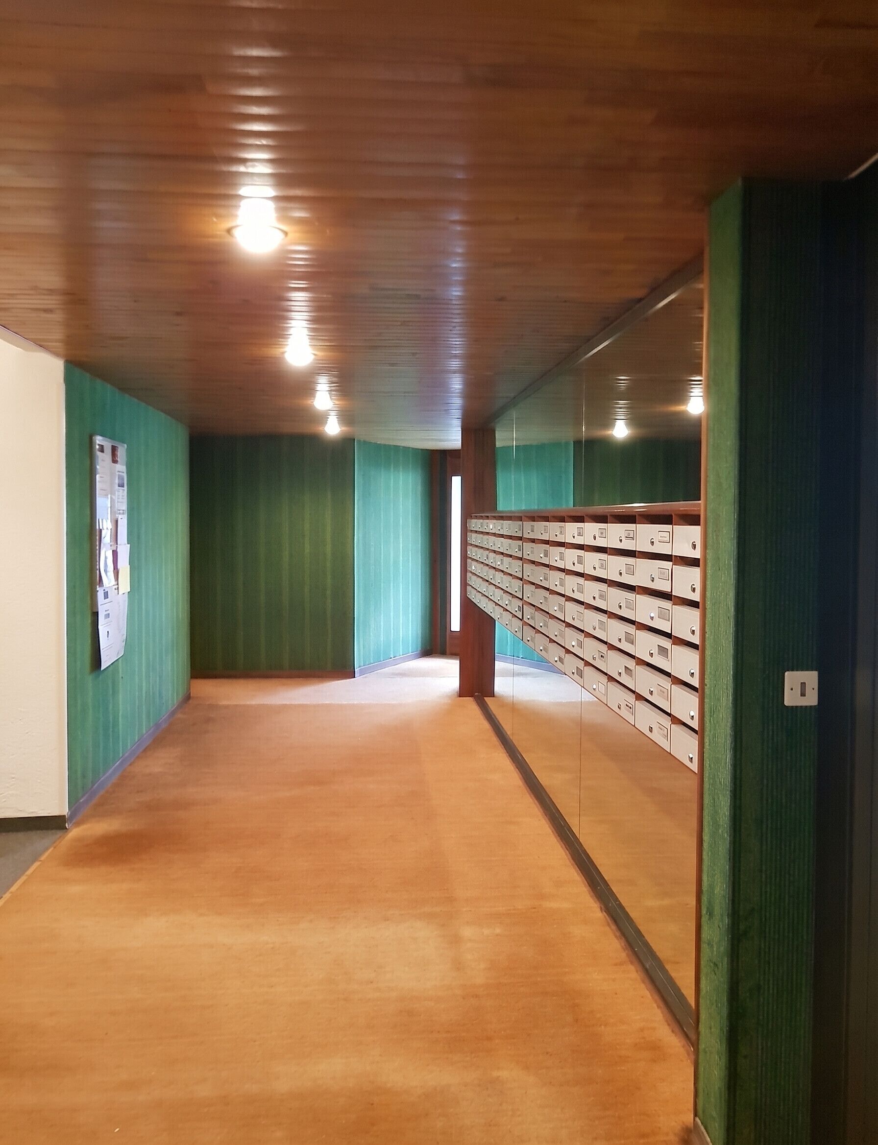 Un passadís amb parets verdes, terres de fusta i una filera de caixes d'emmagatzematge a la dreta.