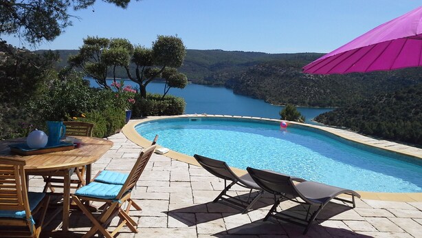 A pool area with lounge chairs and a table, overlooking a lake and hills. - Architect's house, rustic style, will seduce you by its environment  (Esparron-De-Verdon)