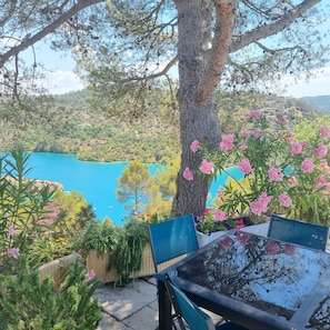 Relax in a serene outdoor seating area overlooking a scenic landscape with a body of water and hilly terrain.