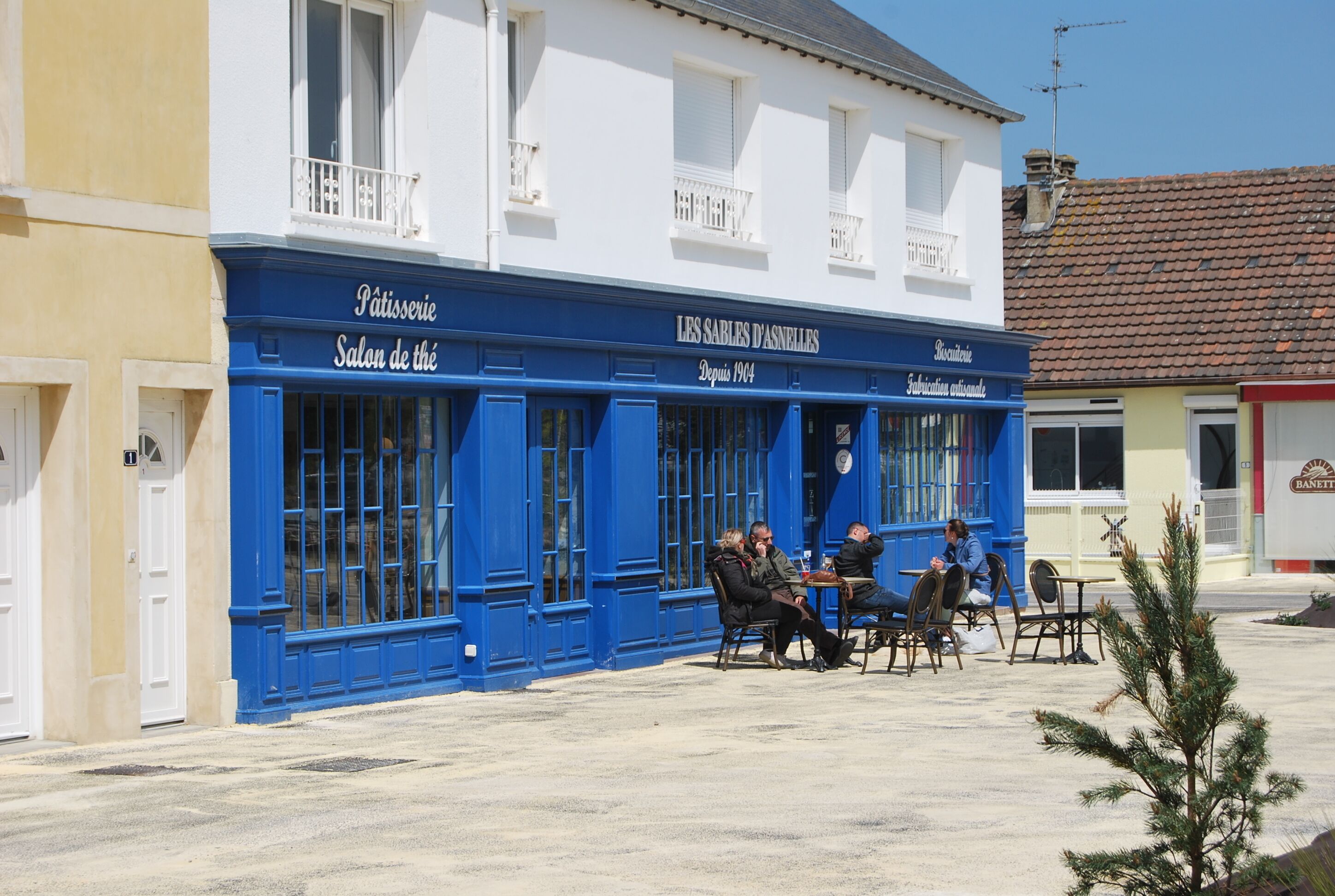 Un edificio con una facciata blu e un cartello con la scritta 'Les Sables d'Asnelles'.