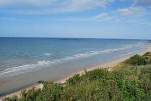 A coastal landscape with a sandy beach and a clear view of the ocean.