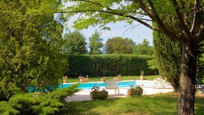 Un giardino con piscina, una sedia e piante in vaso.