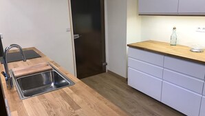 A modern kitchen with a wooden countertop, stainless steel sink, and white cabinets. - Beautiful family home with sea view and beach access (Lancieux)