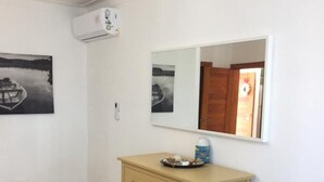 Une chambre à coucher comprenant un lit, une commode, un miroir et deux tableaux accrochés au mur.