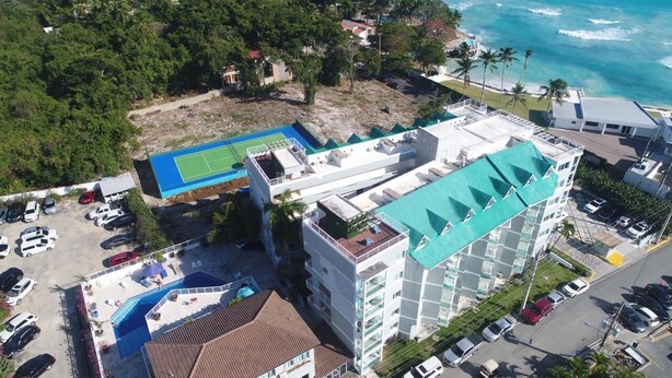 Un hôtel à plusieurs étages doté d’une piscine sur le toit, d’un court de tennis et offrant une vue sur l’océan.