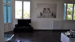 Un salon moderne doté d’une grande fenêtre, d’un téléviseur à écran plat et d’un radiateur.