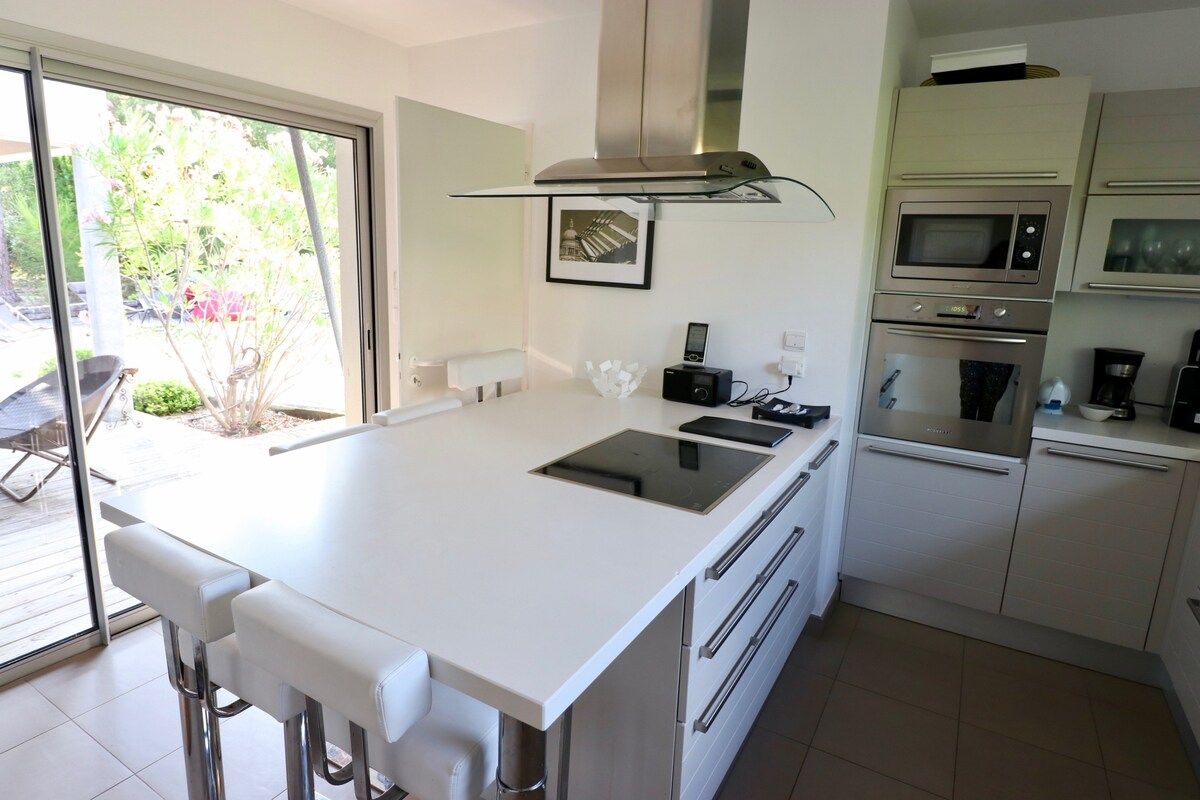 Una cocina moderna con una isla central, hornos empotrados y un ventanal grande.