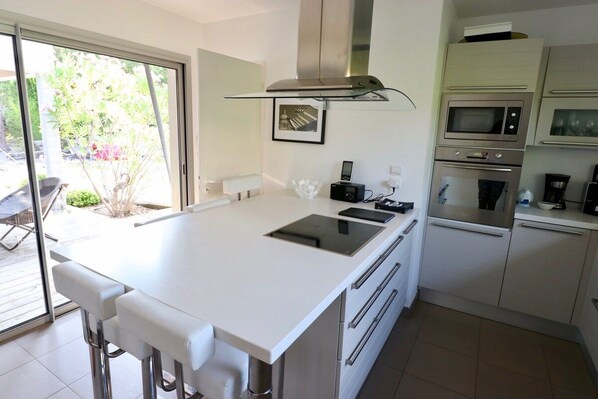 A modern kitchen with a central island, built-in ovens, and a large window.