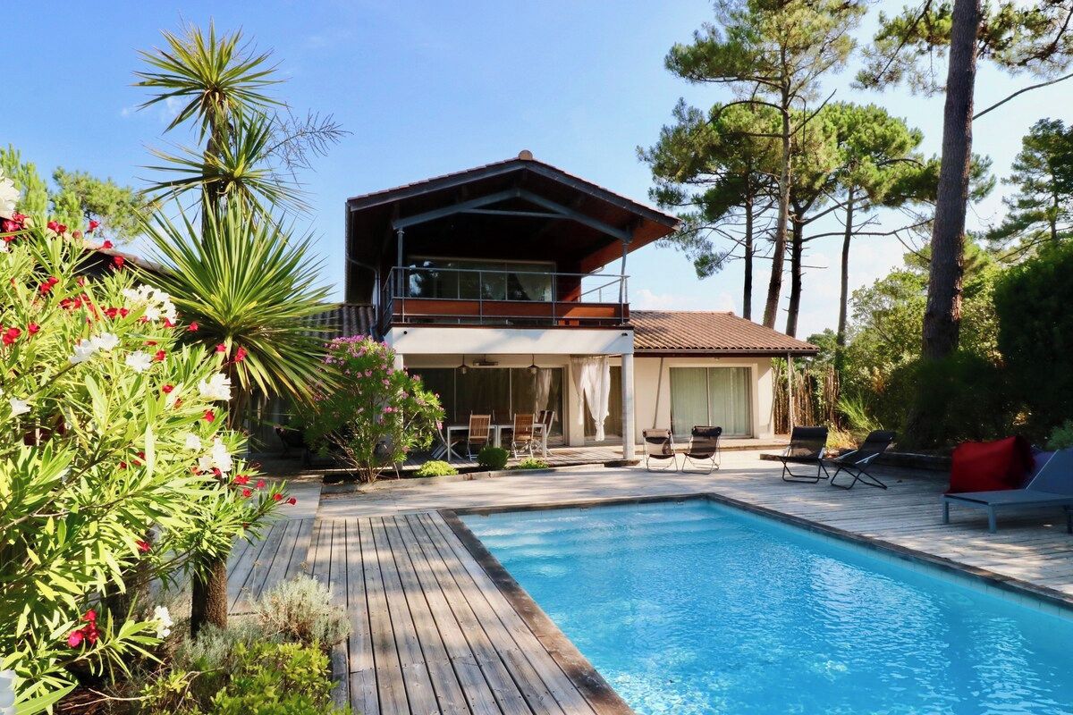 Una casa a due piani con piscina, immersa nel verde e alberata.