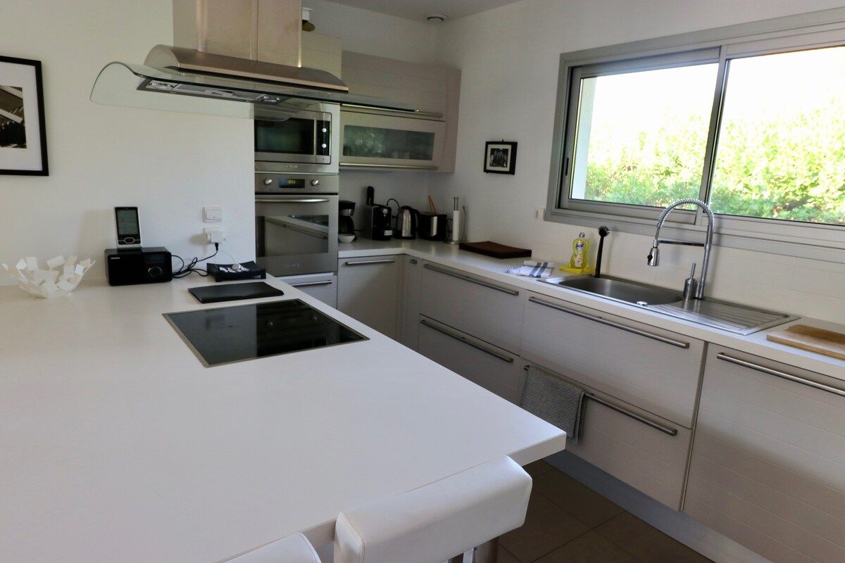 Una cucina moderna con isola centrale, forno integrato e una finestra che offre luce naturale.