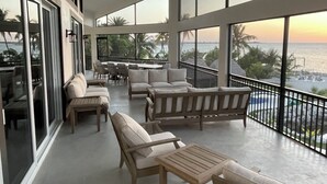 A spacious balcony with multiple seating areas, large windows offering ocean views, and a pool visible through the railing. - 5 bedrooms, Heated/Chilled  Pool, Open Water Views, Boat Dockage, Sleeps 13--15, (Marathon)