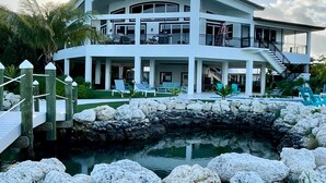 A large, multi-story white building with balconies, a pool, and a stone wall. - 5 bedrooms, Heated/Chilled  Pool, Open Water Views, Boat Dockage, Sleeps 13--15, (Marathon)