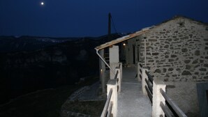 A stone building with a wooden staircase leading to a door. - Former family home : 10 th rental (Braux)