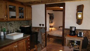 A rustic kitchen with wooden cabinets, a stone sink, and a wooden dining table. - Former family home : 10 th rental (Braux)