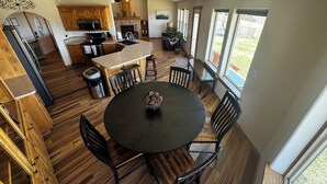 A spacious kitchen with wooden cabinets, a central island, and a dining area with a round table and chairs. - Gateway to Yellowstone, Island Park  (Ashton)