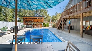 Una piscina con lettini e un'area solarium in legno.