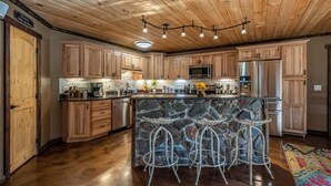 Un'ampia cucina con mobili in legno, un'isola in pietra con sgabelli da bar ed elettrodomestici moderni.