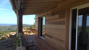 A wooden balcony with a stone bench, a table, and a view of the landscape. - Large house with private pool quiet with views of the Gulf of Santa Giulia (Porto-Vecchio)