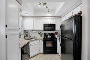 A kitchen with white cabinets, a black refrigerator, a microwave, and a stove. - A Perfect Retreat (Chandler)