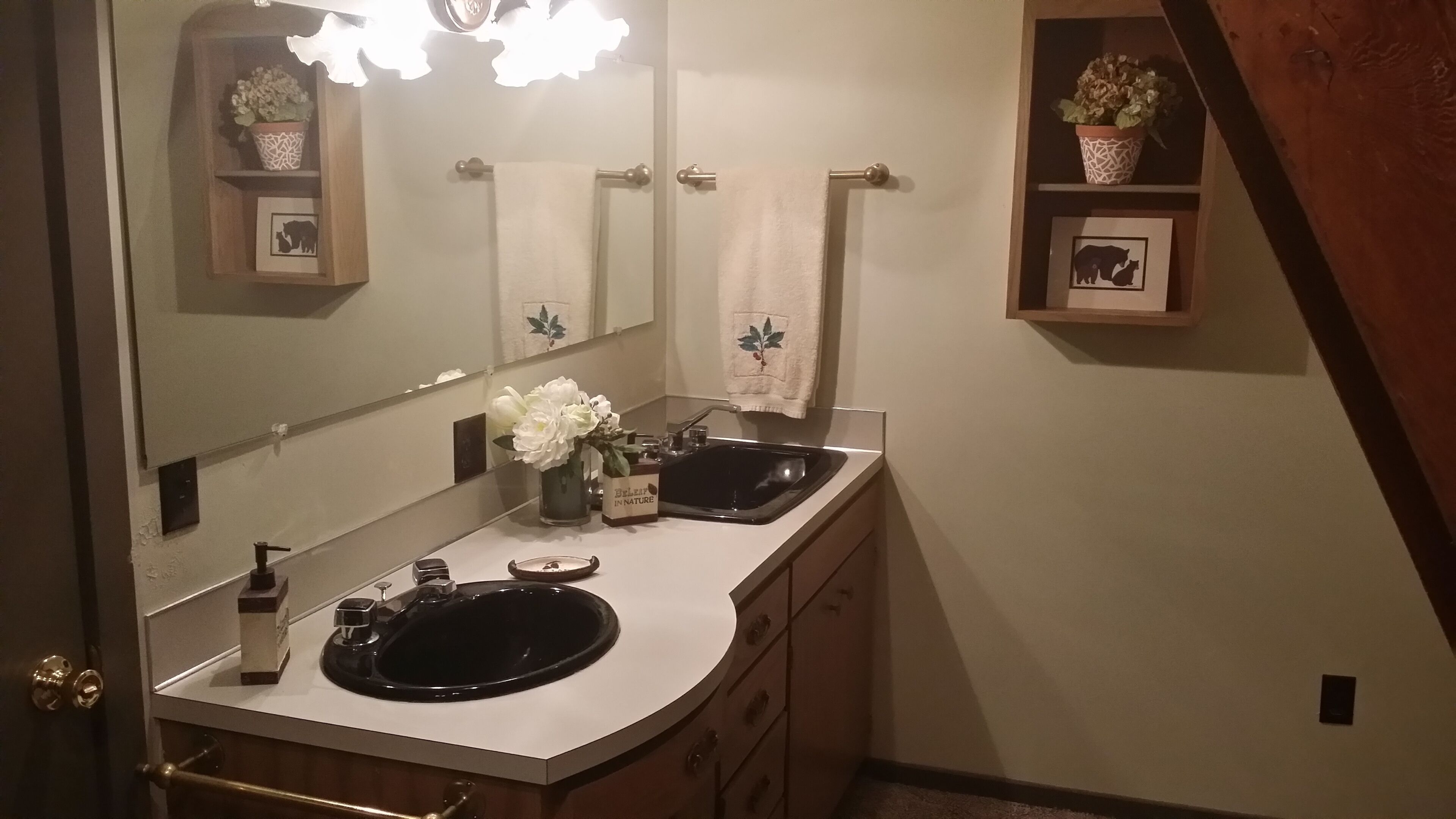 A bathroom with a double sink, a mirror, and a towel rack.