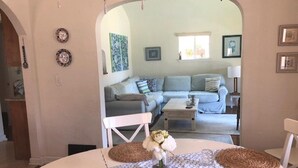 A dining area with a round table, woven placemats, and a vase of flowers.