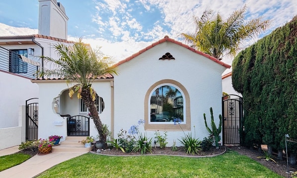 A single-story house with a white exterior, a red-tiled roof, and a small arched window.