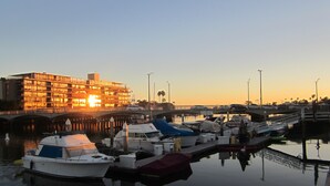 A marina with boats docked, a bridge, and a building with illuminated windows.